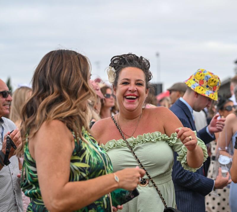 A race goer smiling and dancing to live entertainment at Southwell