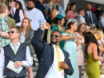 A well dressed man in a suit punches the air in celebration in the grandstand at Southwell