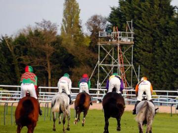 A group of horses and Jockeys running away from the camera