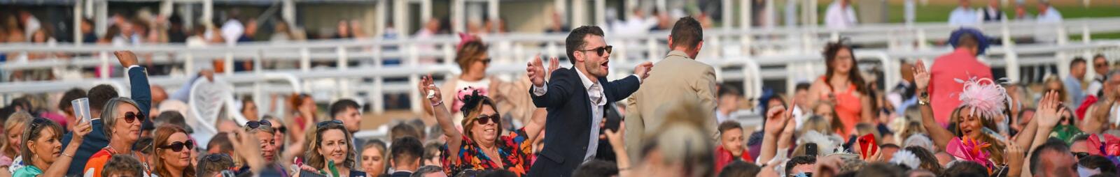 A man on the shoulders of his friends at a music event at Southwell Races
