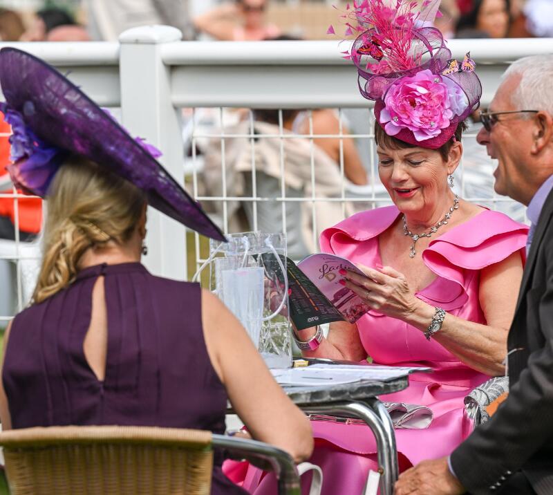 A superbly dressed race goer reads a racecard at Southwell Ladies Day