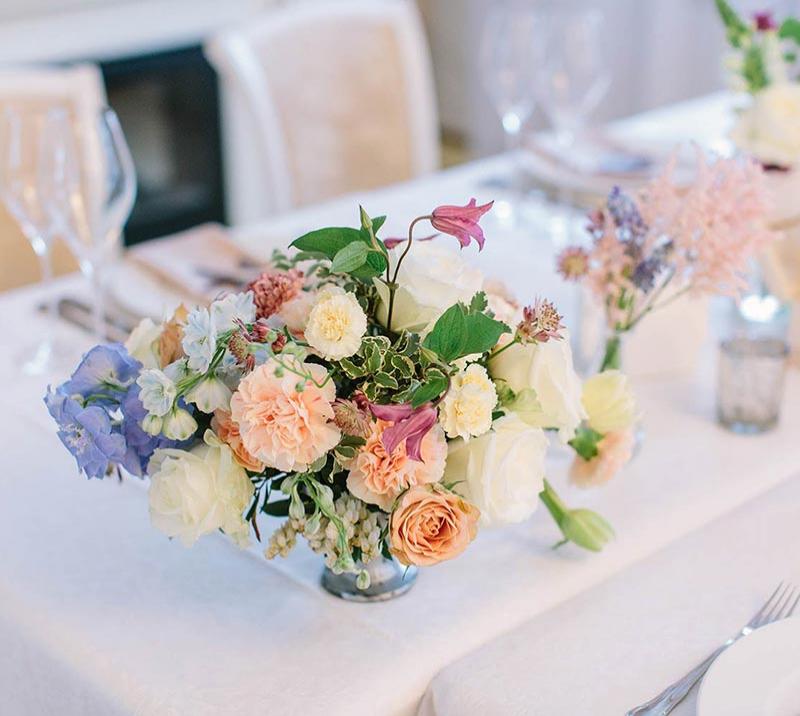 A bouquet of flowers sits on a wedding breakfast table.