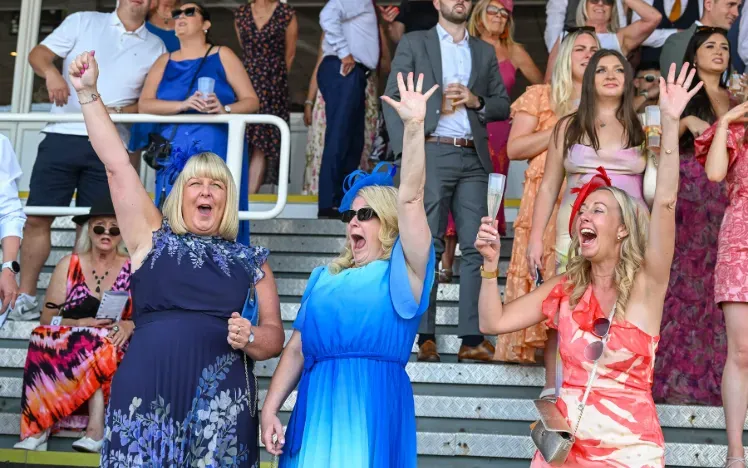 Three race goers cheering happily at Southwell