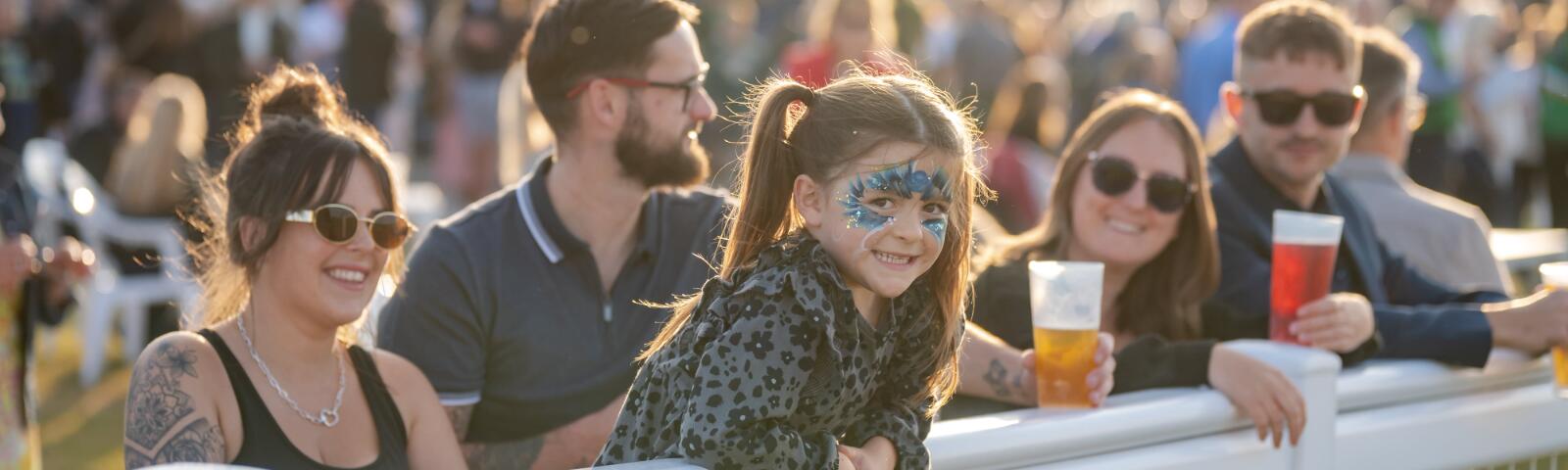 A young child in face paint smiles at the trackside at Southwell