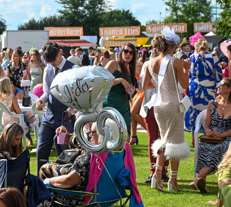 A bride to be and her hen do mark their spot at the races with an 'I Do' balloon.