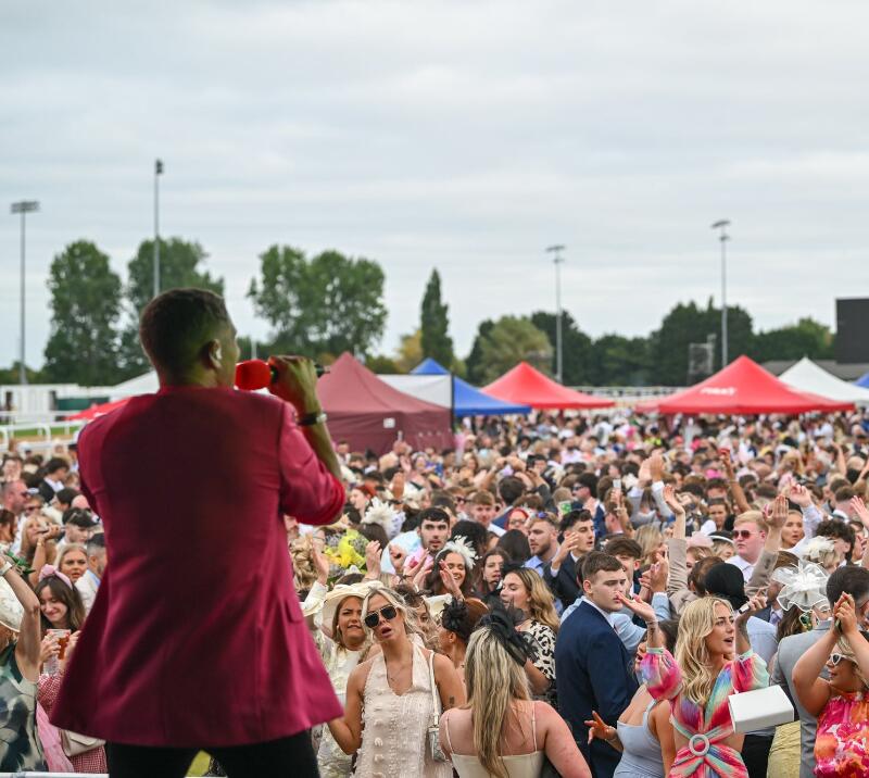 A singer performing for a large crowd at Southwell Races